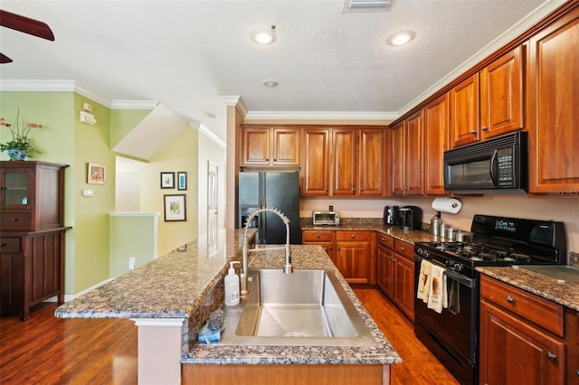 kitchen featuring sink, crown molding, a kitchen island with sink, black appliances, and dark hardwood / wood-style flooring