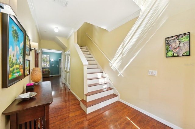 stairway with crown molding and wood-type flooring