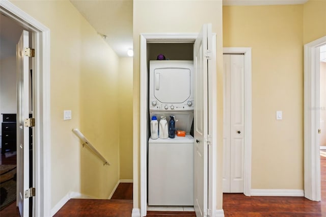 laundry room featuring stacked washer and dryer and dark wood-type flooring