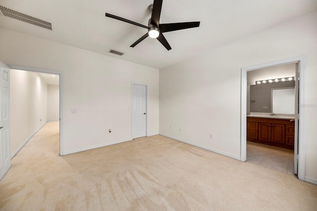 unfurnished bedroom featuring ensuite bathroom, ceiling fan, sink, and light colored carpet