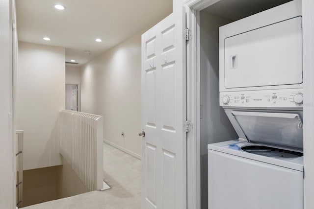 clothes washing area with light carpet and stacked washer / drying machine