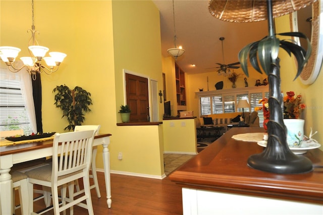 dining room with ceiling fan with notable chandelier, a high ceiling, and dark hardwood / wood-style floors