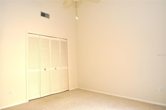 unfurnished bedroom featuring light carpet, a closet, and ceiling fan