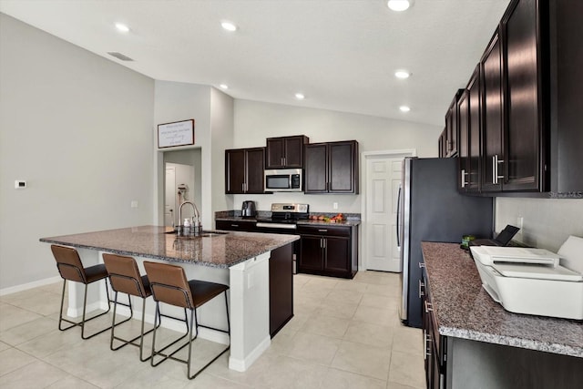 kitchen with an island with sink, stainless steel appliances, sink, vaulted ceiling, and a kitchen breakfast bar