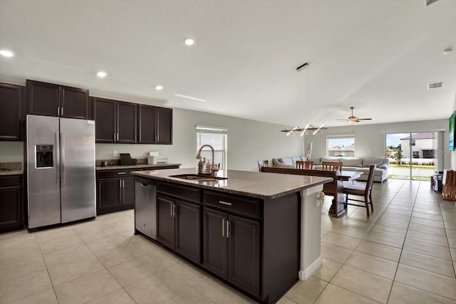 kitchen with light tile patterned flooring, sink, dark brown cabinets, a center island with sink, and stainless steel appliances