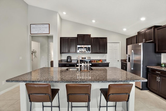 kitchen with an island with sink, appliances with stainless steel finishes, a kitchen bar, and lofted ceiling