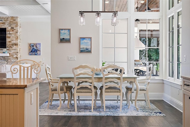 dining room with beam ceiling, dark wood-type flooring, and a wealth of natural light