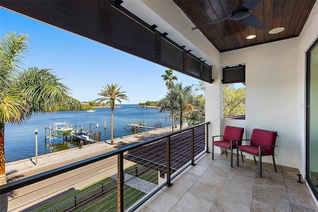 balcony featuring a boat dock, a water view, and ceiling fan