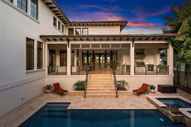 back house at dusk with a patio and a pool with hot tub