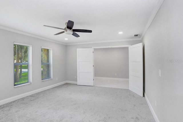 unfurnished room with ceiling fan, light colored carpet, and ornamental molding