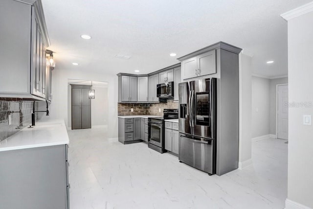 kitchen featuring gray cabinetry, appliances with stainless steel finishes, crown molding, and tasteful backsplash