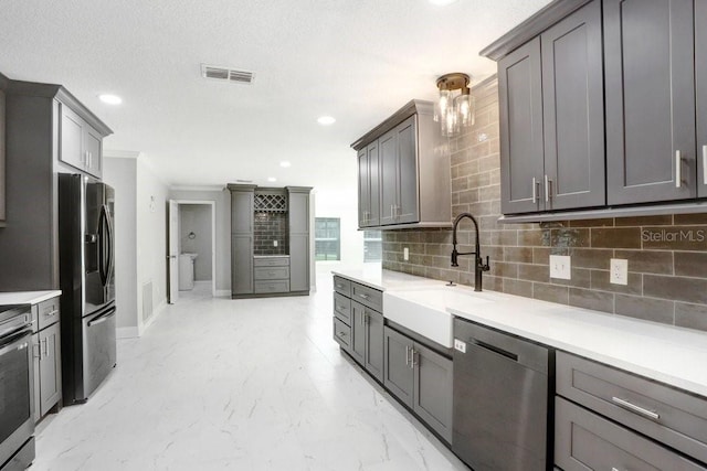 kitchen with crown molding, stainless steel appliances, backsplash, gray cabinets, and sink