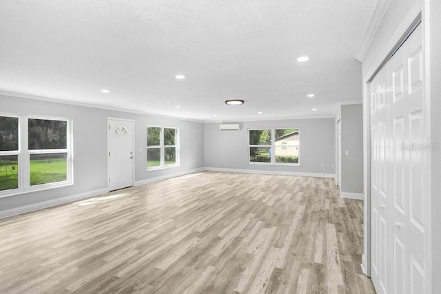 unfurnished living room with a wall mounted AC, light hardwood / wood-style flooring, and crown molding