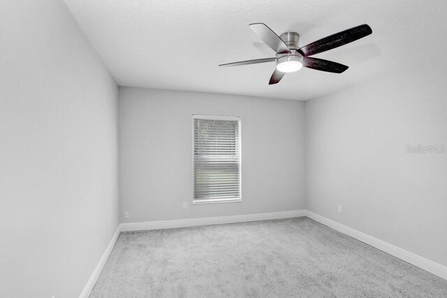 carpeted spare room featuring ceiling fan