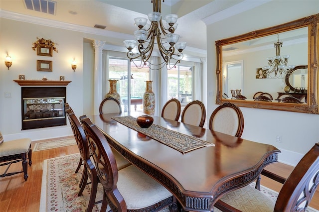 dining space with a notable chandelier, ornamental molding, and light hardwood / wood-style floors