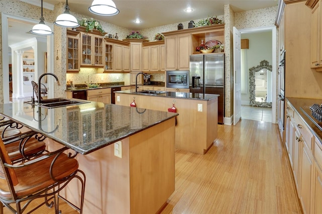 kitchen with decorative light fixtures, sink, a breakfast bar area, a kitchen island with sink, and stainless steel appliances