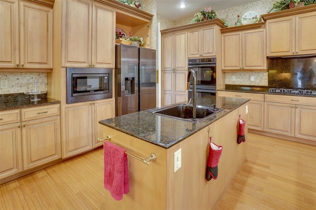 kitchen featuring an island with sink, appliances with stainless steel finishes, sink, and light brown cabinetry