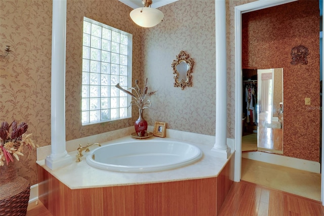 bathroom with ornate columns, wood-type flooring, and a tub