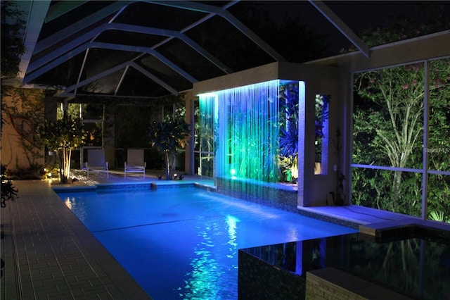 view of swimming pool featuring pool water feature and glass enclosure