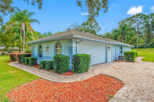 view of side of property featuring central AC unit, a garage, and a lawn