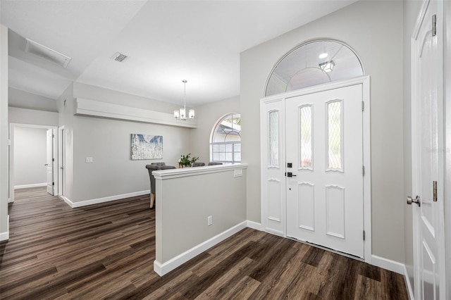 foyer entrance with lofted ceiling, dark hardwood / wood-style floors, and a chandelier