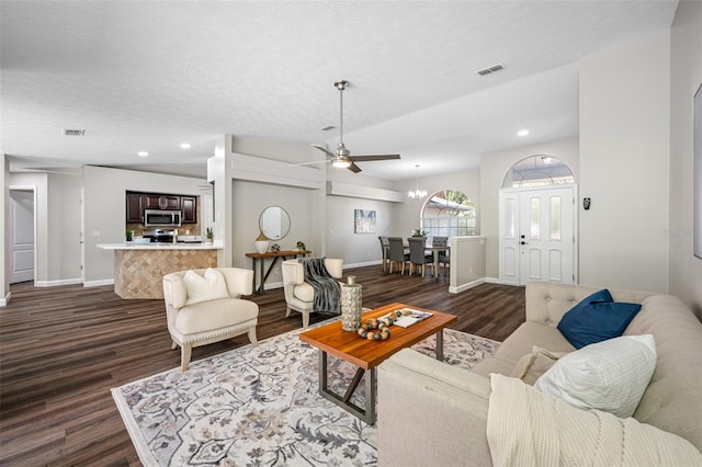 living room with dark hardwood / wood-style floors, a textured ceiling, and ceiling fan with notable chandelier