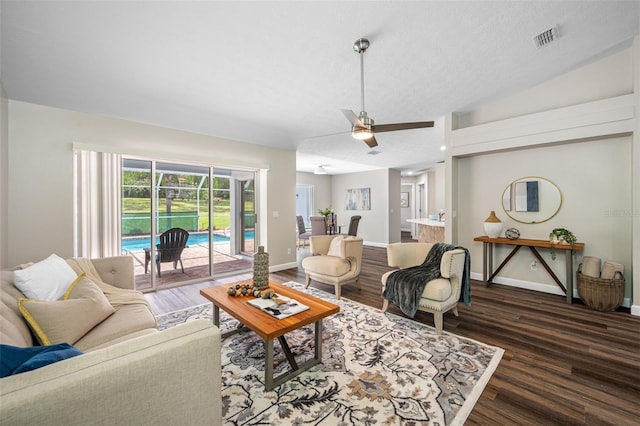 living room featuring dark wood-type flooring, vaulted ceiling, a textured ceiling, and ceiling fan