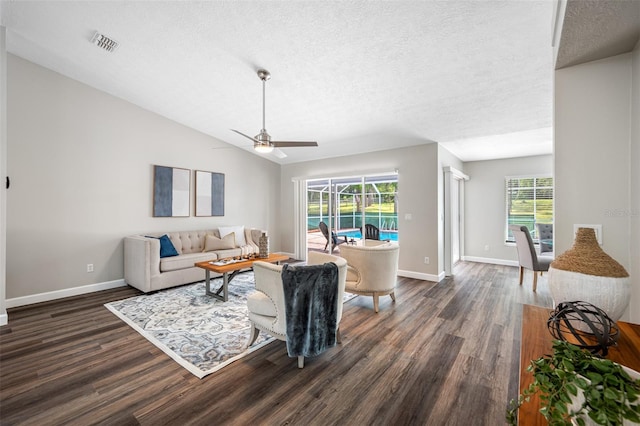 living room with ceiling fan, dark wood-type flooring, vaulted ceiling, and a wealth of natural light