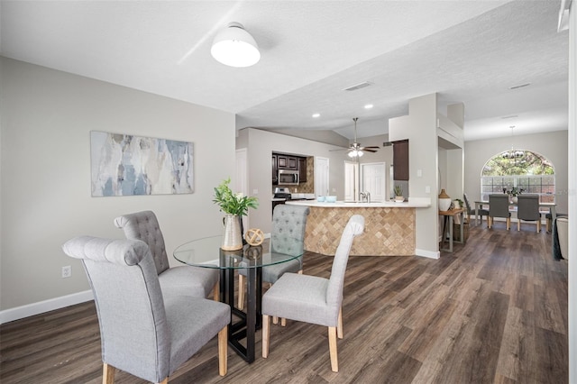 dining space featuring ceiling fan with notable chandelier, a textured ceiling, vaulted ceiling, and dark hardwood / wood-style floors