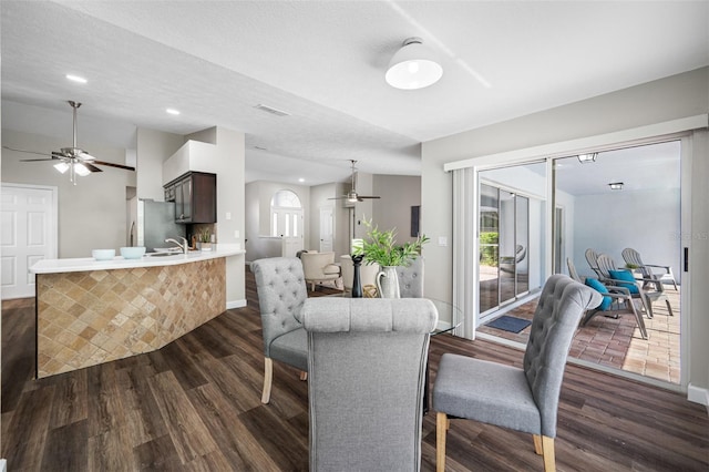 dining area featuring sink, dark wood-type flooring, a textured ceiling, and ceiling fan