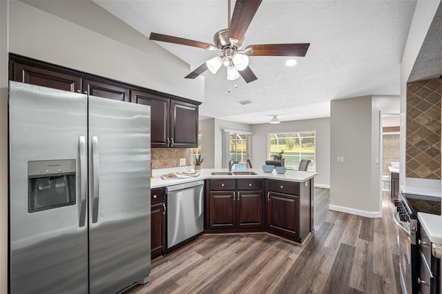 kitchen featuring kitchen peninsula, appliances with stainless steel finishes, a textured ceiling, dark hardwood / wood-style floors, and sink