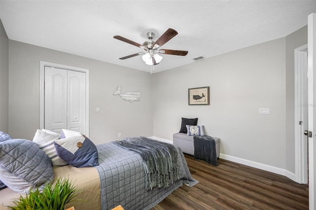 bedroom with a textured ceiling, dark hardwood / wood-style floors, a closet, and ceiling fan