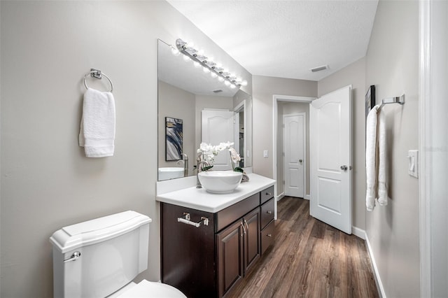 bathroom with vanity, a textured ceiling, hardwood / wood-style flooring, and toilet