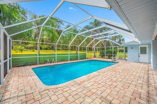 view of swimming pool featuring a yard, a patio area, and a lanai