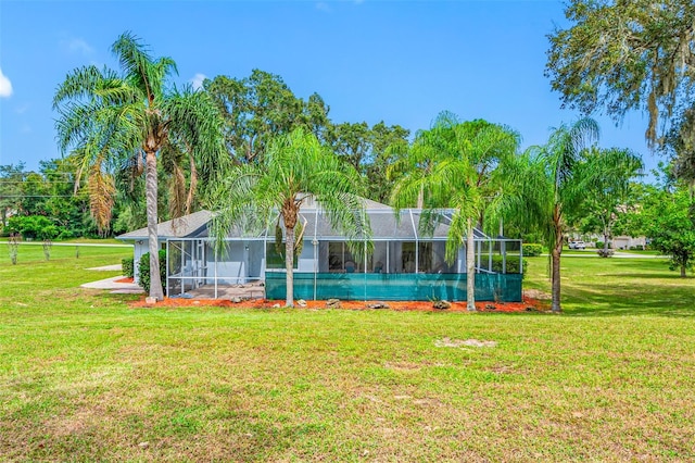 rear view of house featuring a lawn and glass enclosure