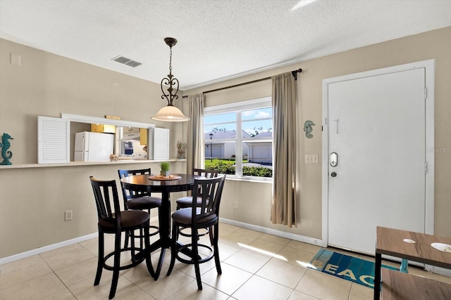 tiled dining room with a textured ceiling