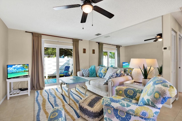 living room with a textured ceiling, light tile patterned floors, and a wealth of natural light