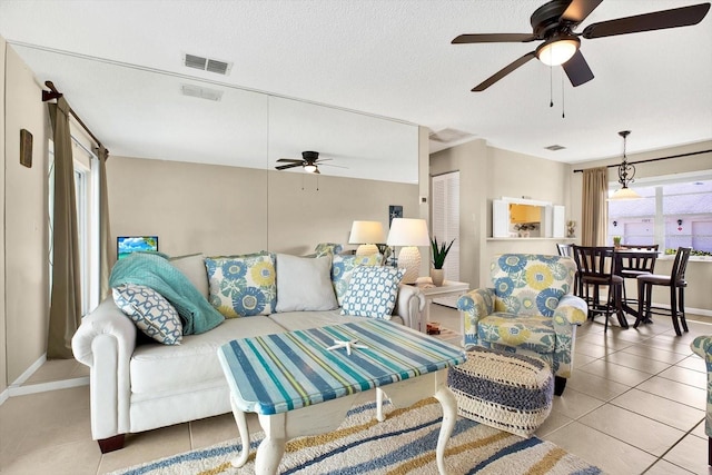 tiled living room with ceiling fan and a textured ceiling