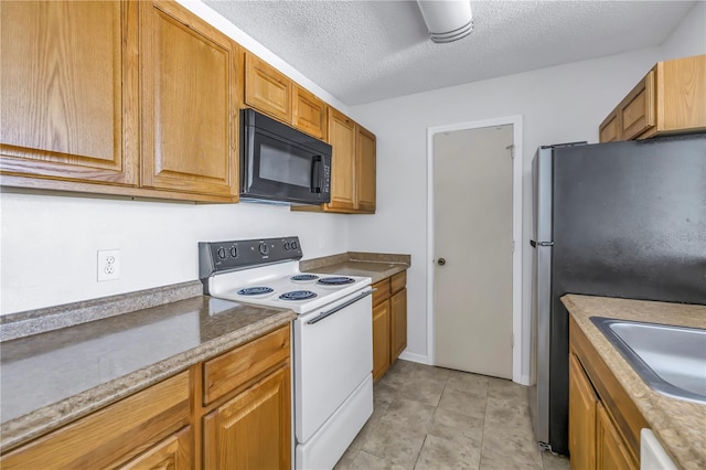 kitchen featuring a textured ceiling, stainless steel refrigerator, white electric range oven, and sink