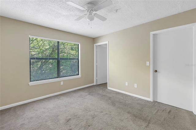 spare room featuring a textured ceiling, light colored carpet, and ceiling fan