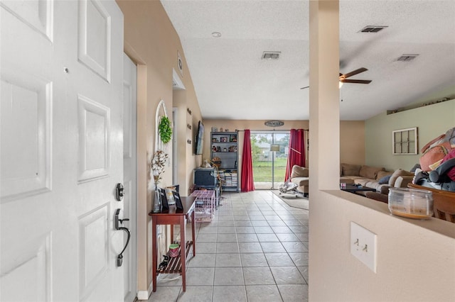 tiled entryway featuring a textured ceiling and ceiling fan