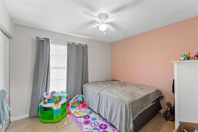 bedroom with a textured ceiling, light tile patterned flooring, and ceiling fan