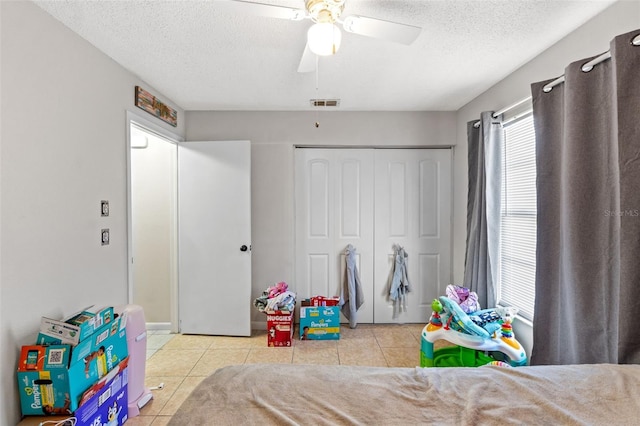 recreation room featuring ceiling fan, a textured ceiling, and light tile patterned floors