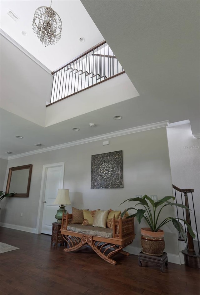 interior space with a towering ceiling, a chandelier, crown molding, and dark hardwood / wood-style flooring