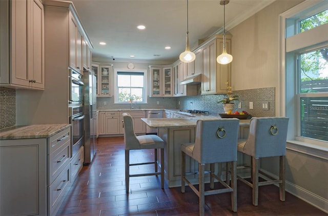 kitchen with hanging light fixtures, decorative backsplash, a breakfast bar, stainless steel appliances, and crown molding