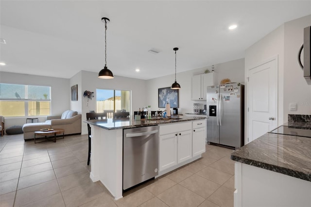 kitchen with white cabinets, appliances with stainless steel finishes, a center island with sink, and a wealth of natural light