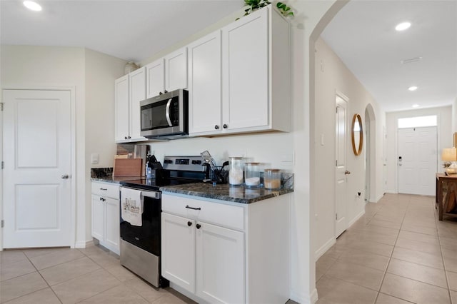 kitchen featuring white cabinets, dark stone countertops, light tile patterned floors, and stainless steel appliances