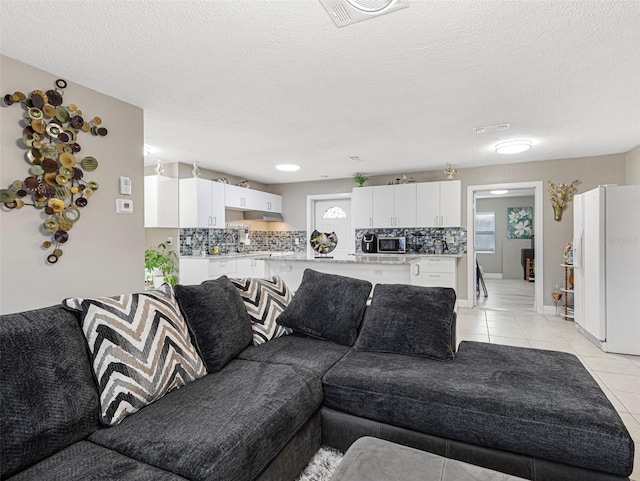 living area featuring visible vents, light tile patterned flooring, and a textured ceiling