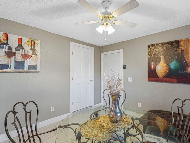 tiled dining area with ceiling fan and a textured ceiling