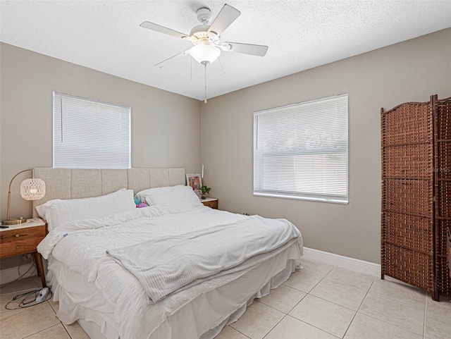 bedroom featuring light tile patterned floors, a textured ceiling, baseboards, and ceiling fan